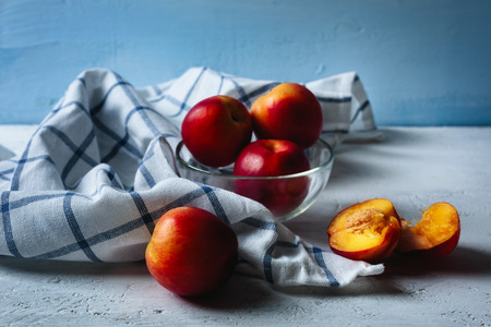 Five ripe nectarines on blue background with checked kitchen towelの写真素材