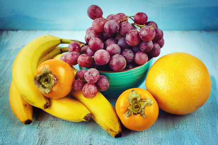 Fresh fruits background. Bananas, grape, persimmon, grapefruit. の写真素材