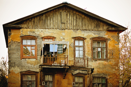 Old damaged house with windows with people live inの写真素材