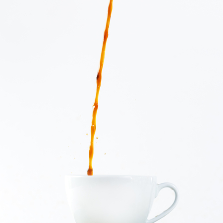 Pouring coffee in a cup on white background. Coffee break, breakfast concept.の写真素材
