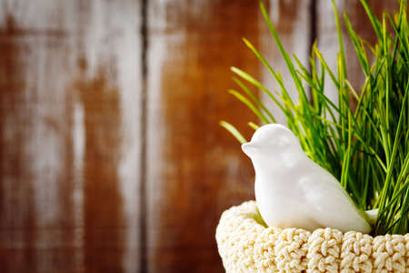 Easter background with and cute white porcelain bird in green grass in the nest. Selective focus.の写真素材