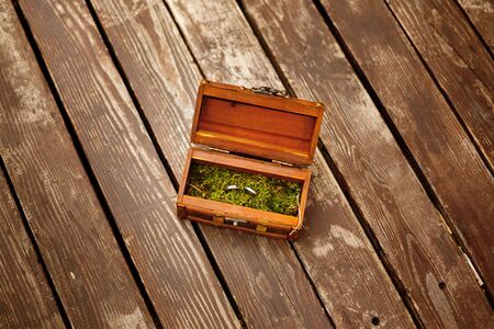 Wedding engagement rings close up lying on moss in wooden box. Rustic style decoration.の写真素材