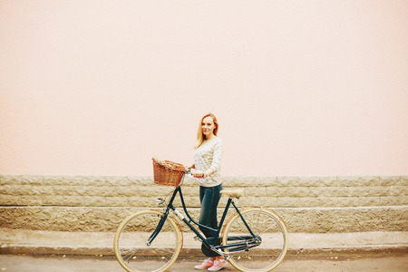 Young Blonde Woman on a Vintage Bicycle standing near Pink Wall in the City. . Selective focus. Grain added.の写真素材