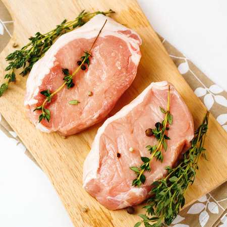 Fresh Raw Pork Meat Steaks served with fresh herbs on white Backgroundの写真素材