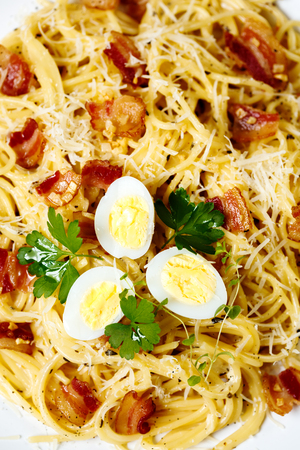 Pasta. Spaghetti with carbonara sauce, parmesan cheese, bacon and quail eggs on wooden table. Italian cuisine.の写真素材