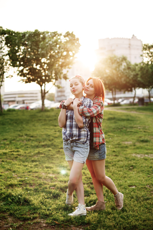 Young Happy Beautiful Best Friends Girls in Pin Up Style Embracing at the Sunset. Friendship Concept. Selective Soft Focus.の写真素材