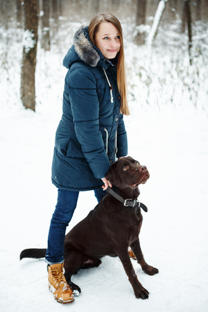 Young Beautiful Woman Playing with Her Dog in Winter Park. Lifestyle Concept, Winter Activities.の写真素材