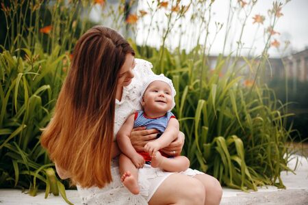 Cute Happy Toddler Sitting on Loving Mother`s Knees and Smiling. Family Fun. Selective Focus.