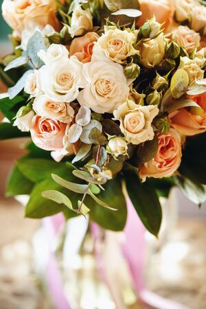 Fresh Bouquet with White and Cream Little Roses and Fresh Green Leaves. Wedding Flowers. Selective Focus.の写真素材