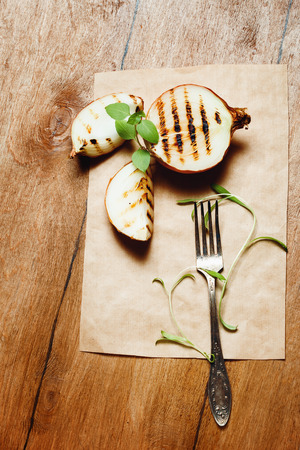 Grilled Onion with Fresh Basil and Tarragon with Vintage Fork on Wooden Table. Rustic Style, Top View.の写真素材