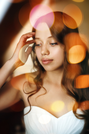 Wedding Day. Portrait of Young Gentle Bride Looking Away. Bokeh Lights Added for Romantic Mood. Selective Focus.の写真素材