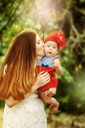 Portrait of Loving Young Mother Holding and Kissing Her Baby. Sunlight, Selective Focus.の写真素材