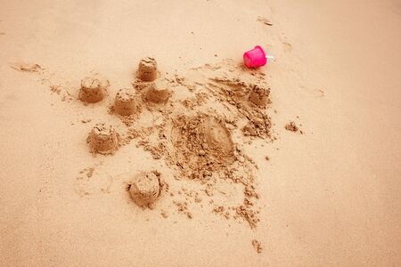 Child`s Sand Castles on a Beach or in Sandbox with Little Pink Plastic Bucketの写真素材