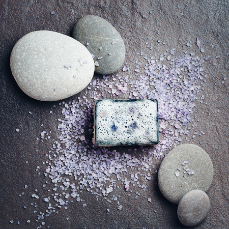 Spa and beauty treatment composition with soap, sea salt and massage stones on darkの写真素材