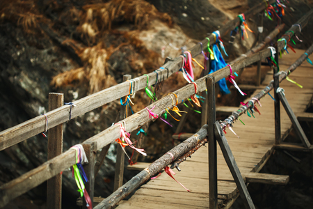 Wooden bridge above mountain river in autumn with traditional buddhism ribbons. Nature background.の写真素材