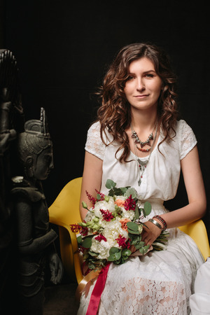 Young brunette bride with flowers in loft interior. Woman looking in camera.の写真素材