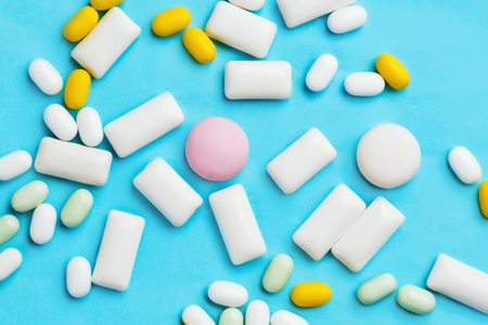 Heap of different chewing gums, mint candies and drops on bright blue backgroundの写真素材