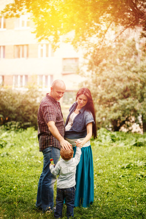 Full-body of happy family in city park at the sunset. Mother, father and little son.の写真素材