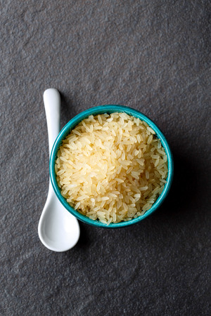 Food background, rice close-up in ethnic bowl on dark surface, top view, vertical compositionの写真素材
