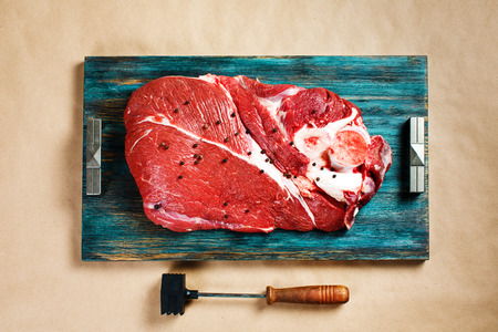 Top view of fresh beef veal meat on rustic wooden tray with meat hammerの写真素材