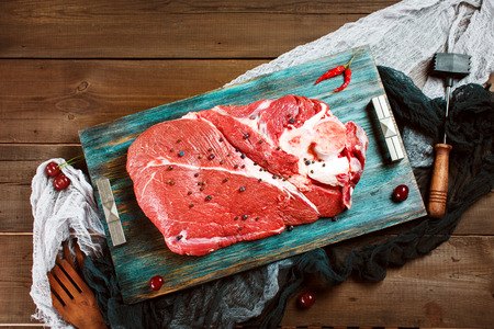 Fresh beef veal meat on rustic wooden table with kitchen utensilsの写真素材