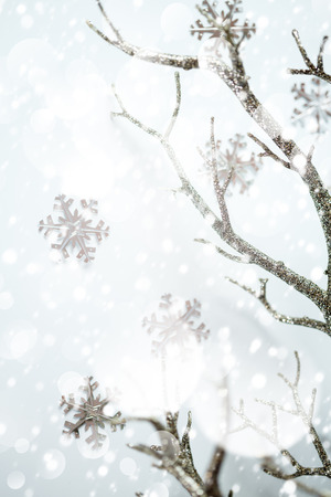 Christmas border, silver branch and metallic snowflakes over light background with snow falling. Selective focus. Space for text.の写真素材
