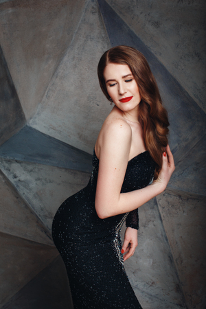 Beautiful sexy woman posing in luxury black dress in loft interior. Portrait of stylish seductive woman.の写真素材