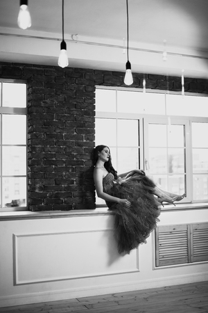 Black and white art portrait of pensive beautiful woman sitting on windowsill. Retro styled woman portrait. Selective focus. Retro concept.の写真素材