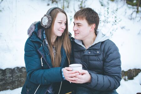Loving couple having fun outdoors in winter, holding big cup with hot teaの写真素材