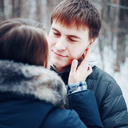 Young loving couple embracing in winter forest, winter vacation concept, toned, selective focus on manの写真素材