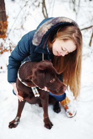 Young woman with labrador dog in winter forest, winter vacations conceptの写真素材
