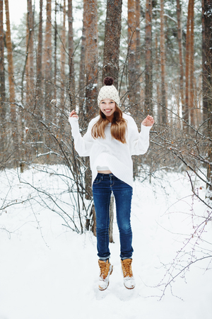 Young woman in cozy clothes having fun in winter forest. Winter vacations and activity.の写真素材
