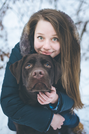 Young woman walking with labrador dog in winter forest, winter holidays concept, close-upの写真素材