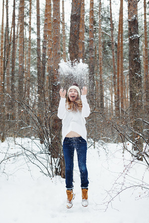 Young woman in cozy clothes having fun in winter forest. Winter vacations and activity.の写真素材