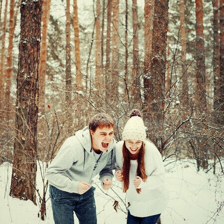 Loving couple having fun and laughing in winter forest, winter vacations, tonedの写真素材