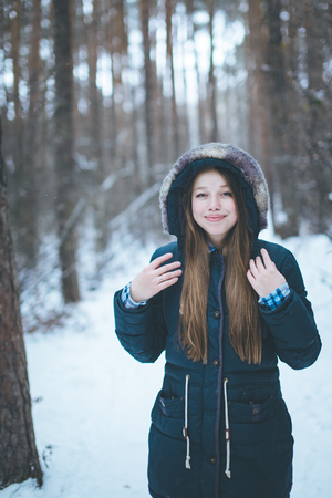 Natural young woman in winter forest walkingの写真素材