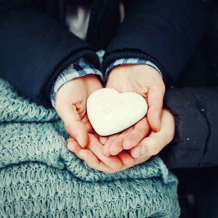 Man and woman hands holding gingerbread heart in white icing, close-up. Valentine day holiday. Tonedの写真素材