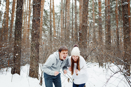 Young funny couple having fun in snowy forest. Winter holidays concept. Pine tree forest.の写真素材
