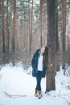Natural young woman in winter forest walking among treesの写真素材