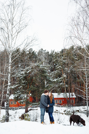 Couple in love having fun with labrador dog, winter forest at the backgroundの写真素材