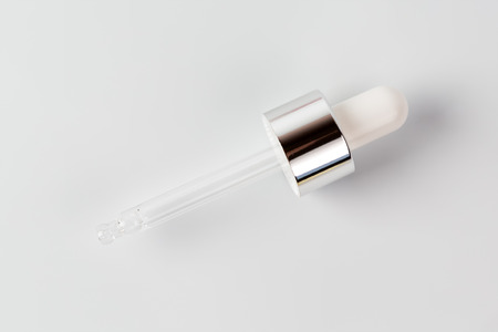 Essential oil or serum in pipette, white backgroundの写真素材