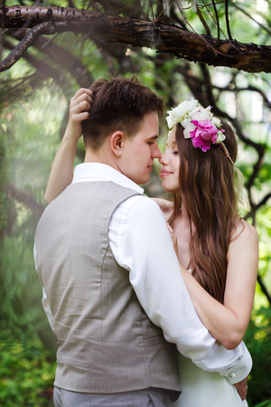 Happy newlywed couple posing at the nature, embracing and kissingの写真素材