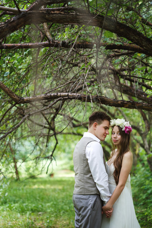 Happy newlywed couple posing at the nature, holding handsの写真素材