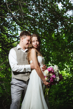 Wedding couple kissing in the park, bride holding flowersの写真素材