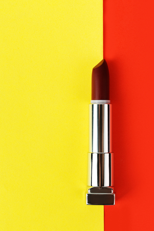 Open dark red lipstick on red and yellow background, flat layの写真素材
