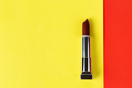 Open dark red lipstick on red and yellow background, flat layの写真素材