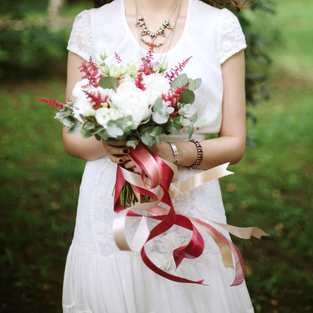 Close-up of wedding flowers with flying ribbons in hands of beautiful womanの写真素材