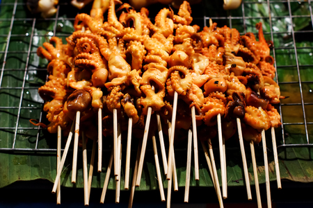 Street food preparing outdoors in Asian country, grilled bbq octopuses on sticksの写真素材