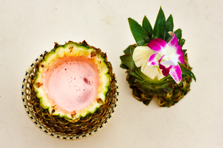 Exotic cocktail, pina colada in an open pineapple at the beach, top viewの写真素材