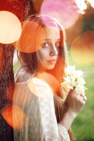 Portrait of young romantic woman with spring flowers, natural beauty. Bokeh light.の写真素材